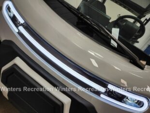 Close-up of a vehicle's front with sleek LED lights and a modern design.