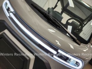 Close-up of a vehicle's front with modern LED headlights and a windshield, showcasing sleek design elements.